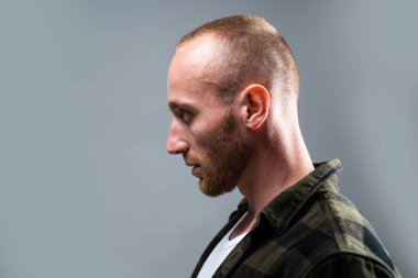 Genç adamın bakışlarını başka yöne çevirdiği bir stüdyo fotoğrafı. Kendine güveni olan yakışıklı bir adamın profili..