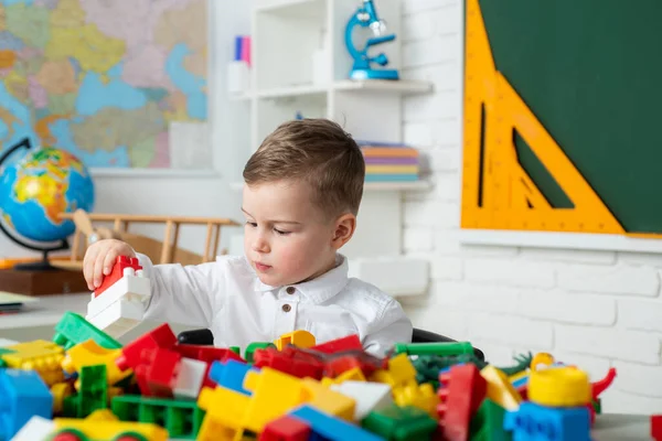 Peuter kind jongen spelen met speelgoed ontwikkelen en leren activiteiten. Schattig kind zit binnen aan een bureau. Kind van de lagere school. Begrip onderwijs en lezen. — Stockfoto