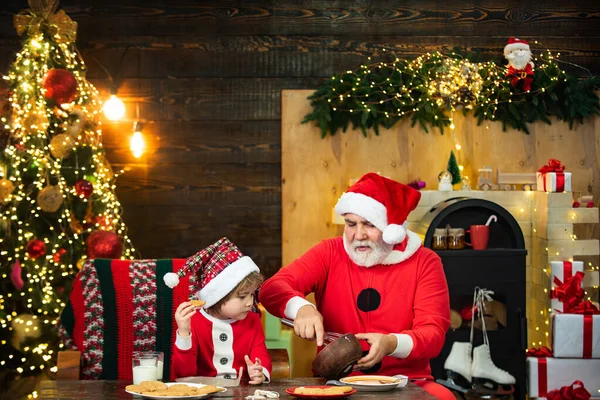 Santa helper. Happy father and son in Santa hat with cookies have a Christmas. Christmas interior. Happy new year. Christmas Celebration holiday.