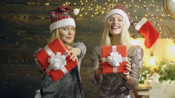 Dos jóvenes felices Santa niña en la celebración de Navidad con regalo de Año Nuevo en casa. amigas divirtiéndose, vestidos de lujo, riendo y felicidad, caras divertidas. — Vídeo de stock