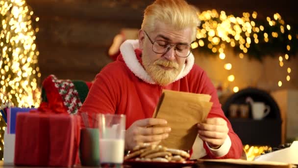 サンタクロースは家にいる。サンタは屋内でクリスマスの夜に家の中で願い事リストの手紙を受け取る準備をします。新年明けましておめでとう. — ストック動画