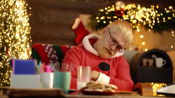 Papá Noel aburrido. Cansado Santa Claus durmiendo en la mesa en casa. — Vídeos de Stock