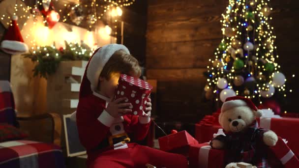 Criança bonito feliz em chapéu de Papai Noel com presente ter um Natal. Feliz Natal e Boas Festas. Ambiente de Natal em casa. Ano Novo crianças. — Vídeo de Stock