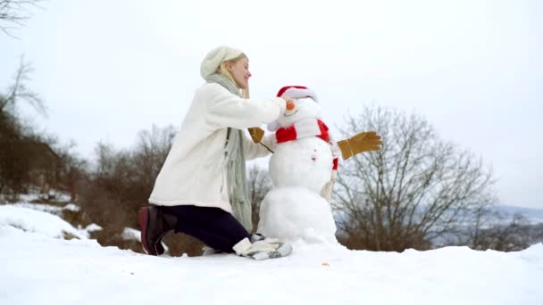 Fille faire bonhomme de neige en plein air le jour d'hiver. — Video