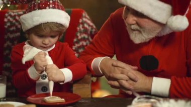 Noel Baba 'nın aile için hazırladığı Noel kurabiyeleriyle sevimli çocuğun yüzünü kapat. Büyükbaba ve torun yeni yıla hazırlanıyor..