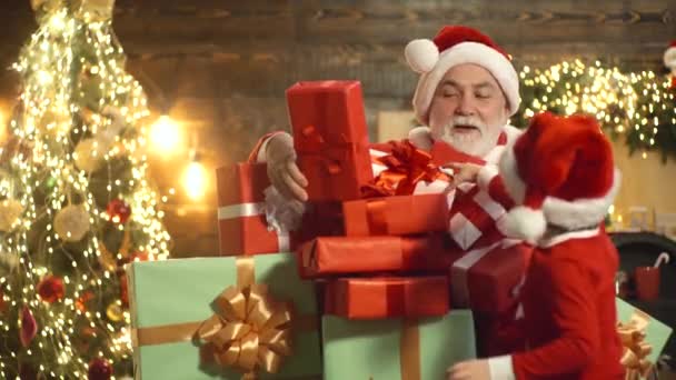 Santa Claus y niño cerca de la chimenea y el árbol de Navidad con regalos. Feliz Navidad y Feliz Año Nuevo. — Vídeos de Stock