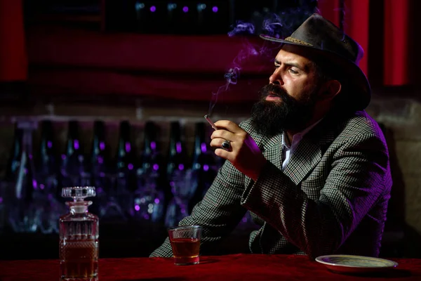 Retrato de um homem barbudo bonito, com um copo de álcool nas mãos. Descanso e relaxamento. — Fotografia de Stock