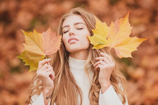Menina beleza ao ar livre desfrutando da natureza. Bonito outono modelo feminino detém uma folha amarela perto do rosto. Retrato de moda mulher esconde seu rosto amarelo folhas de bordo. Folhas caindo e conceito de pessoas. — Fotografia de Stock