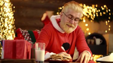 Noel Baba, Noel ağacının arka planındaki istek listesini kontrol eder.