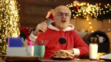Mutlu Noeller ve yeni yıl konsepti. Modern komik Noel Baba film izliyor. İnsani duygular. Noel Baba boş zamanın tadını çıkarıyor..