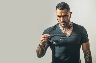 Güneş gözlüklü yakışıklı, kendine güvenen bir adam. Stüdyoda poz veren ciddi biri. Erkekler cinsellik, cazibe ve karizma.