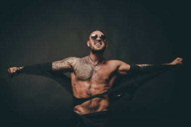 Öfkeli adam siyaha izole edilmiş. İnsan gücü. Kaslı üstsüz erkek model. Atletik genç adam gömleğini yırttı ve mükemmel çıplak vücudunu gösterdi..