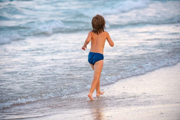 Lindo niño que se divierte y corre en la playa de arena en verano. — Foto de Stock