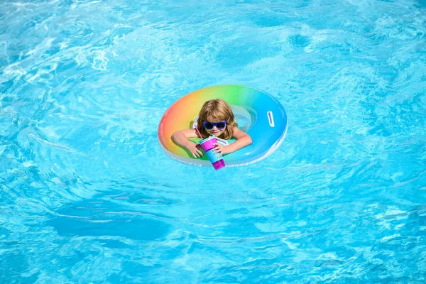 Söt rolig liten småbarn pojke i en färgglad baddräkt och solglasögon koppla av med leksak ring flyter i en pool har roligt under sommarsemester i en tropisk resort. Panorama blå havsvåg. — Stockfoto