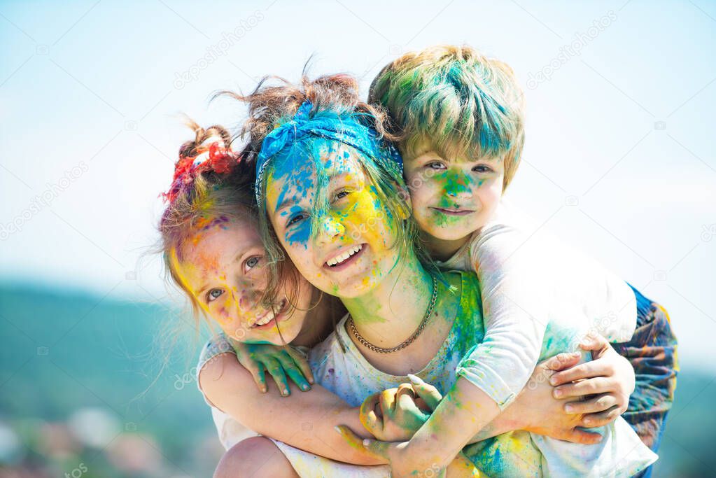 Cute children with colorful paint powder on faces, close up portrait of happy cute litttle kids on holi color festival.