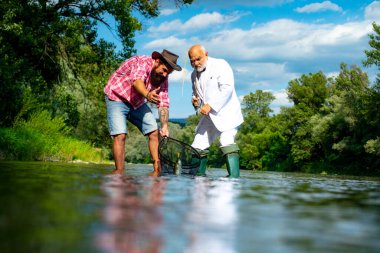 Hobi spor aktivitesi. Sakallı balıkçılar. Oltayı oltaya takın. Normalde balıklar vahşi doğada yakalanır. Doğal ortamda rahatla. Göl kenarında dinlenen ve balık tutan bir adam. Balık tutan adam..