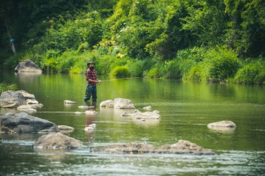 İnsan balıkçı balık yakalar. Balık tutma becerileri. İnsanoğlunun uçan balık hobisi. Nehirde balık tutan neşeli bir balıkçı. Yaz tatili. Balıkçılık dikkatli ve tam bir an içinde hazır olmayı gerektirir..