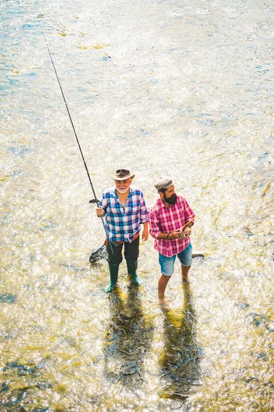 Padre e figlio adulto pesca sul lago. Un pescatore barbuto. Uomo maturo pesca a mosca. State calmi e pescate. Il concetto di vita di lusso. Uomo anziano andato a pesca. — Foto Stock