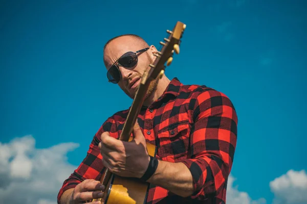 Man wearing sunglasses and playing guitar on sky. Camping holiday. — Stock Photo, Image