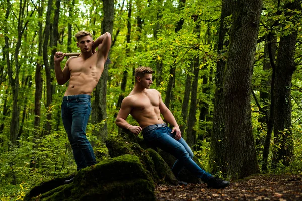 Мужская сила. Мускулистые модели без рубашек и джинсовые штаны. Модные жестокие парни с сексуальным обнаженным туловищем в лесу. — стоковое фото