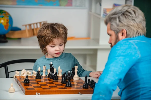 Cute little boy playing chess with Parents. Handsome teacher giving private lessons chess to preschool boy. Educational games.
