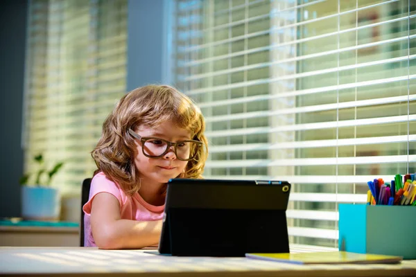 Smart little boy watch online video lesson at home, small child in glasses have web video class on computer, study at home, homeschooling concept.