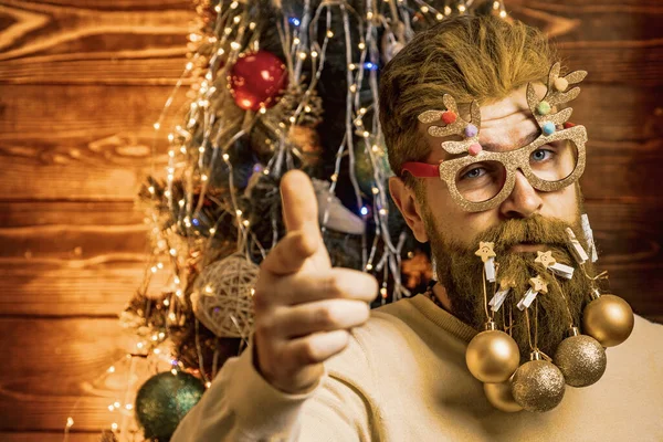Baard man heeft plezier in de buurt van de kerstboom binnen. Nieuwjaar Kerstconcept. Knappe man in kerstjurk. — Stockfoto