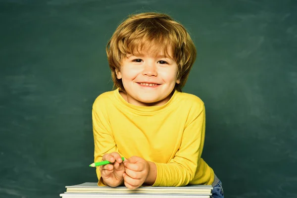 학교나 학생들은 부모들에게 좋은 성적으로 시험을 보여 줍니다. 학생들. 책상 근처에서 학교 용품을 가지고 행복 한 얼굴 표정을 짓고 있는 귀여운 소년 — 스톡 사진