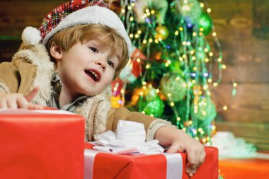 Kış çocuğu. Ahşap ev geçmişinde Noel hediyesi olan bir çocuk. Noel hediyesi kutulu mutlu çocuk. Çocuklar için kış teslimatı. Noel çocukları.