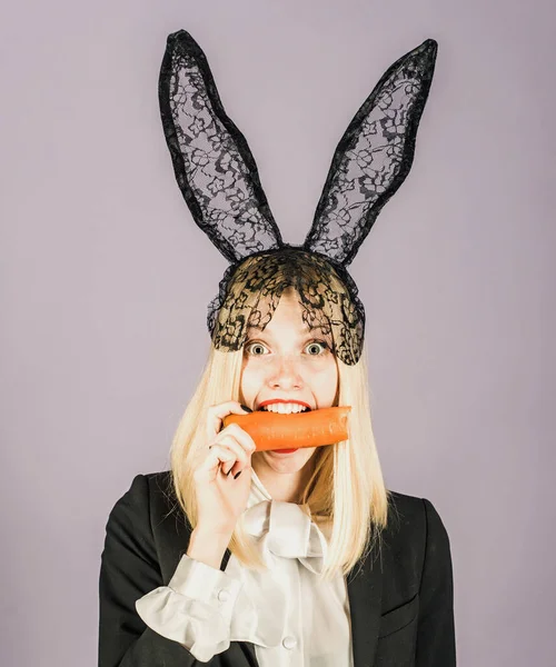 Mujer conejita sorprendida usando orejas de conejo y comer zanahoria. Feliz Pascua y divertido día de Pascua. Sonríe pascua. — Foto de Stock