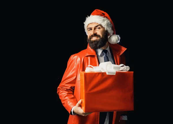 Weihnachtsmann mit roter Weihnachtsgeschenkschachtel. Der bärtige moderne Weihnachtsmann auf schwarzem Hintergrund wünscht frohe Weihnachten und ein gutes neues Jahr. Weihnachtsmann auf schwarzem Hintergrund isoliert. — Stockfoto
