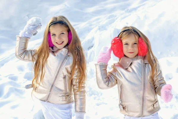 Feliz invierno. Dos niñitas jugando con nieve en el parque. Retrato de dos niñas jugando con nieve en invierno. Linda hermanas jugando en una nieve. —  Fotos de Stock