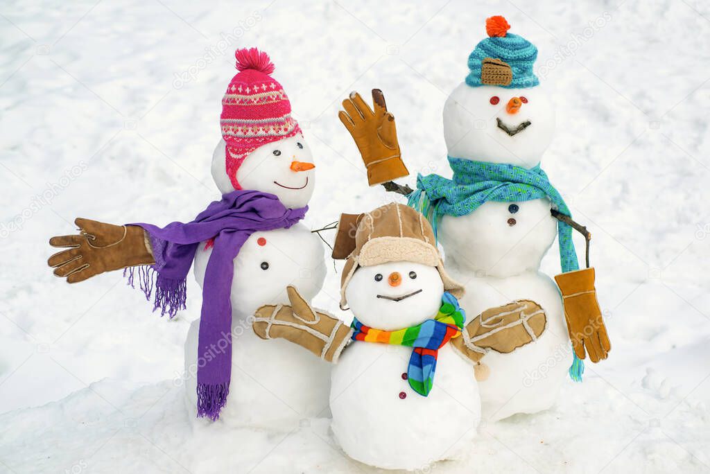 Happy snowman couple and snowman child with Christmas gift standing in winter Christmas landscape. Merry Christmas and happy New Year.