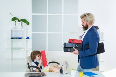 İş adamı olmanın hayalini kuran küçük çocuk. Çocukluk ve rüya kavramı. Patron ve işadamı ofiste birlikte çalışıyorlar..