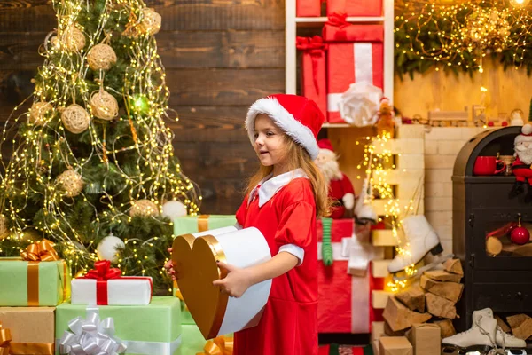 Αστείο παιδί που κρατάει Χριστουγεννιάτικο δώρο. Παιδί με χάρισμα. Μοντέλα παιδί διασκεδάζει με το δώρο. Το παιδί διασκεδάζει κοντά στο χριστουγεννιάτικο δέντρο μέσα. Χριστουγεννιάτικα παιδιά. Σας εύχομαι Καλά Χριστούγεννα.. — Φωτογραφία Αρχείου