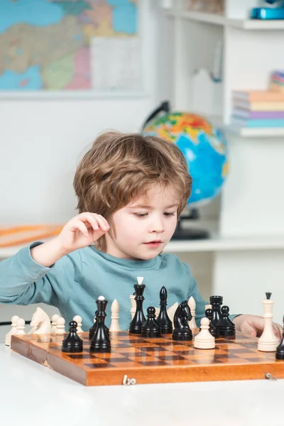 Boy kid playing chess at home. Chess school. Clever concentrated and thinking child while playing chess. Games and activities for children. Family concept.