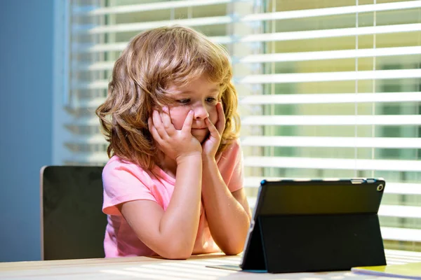 Kid at online school, home schooling. Little child boy have on-line lesson conversation with remote teacher, use laptop, study indoors.