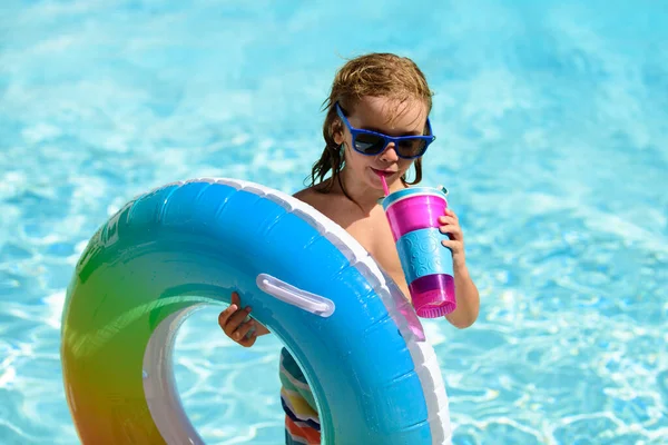 Güneş gözlüklü çocuk ve yaz kokteyli. Yüzme havuzunda yüzen oyuncak yüzükle rahatlıyor.. — Stok fotoğraf