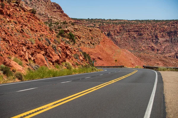 Paesaggio con rocce arancioni, cielo con nuvole e strada asfaltata in estate. Viaggio su strada americano. — Foto Stock