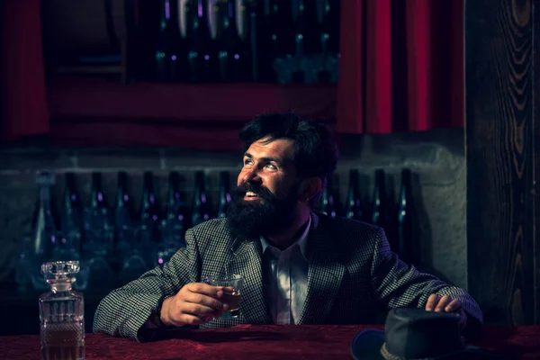 Handsome bearded man enjoying whiskey in bar. Hipster drinking a brandy in bar. — Stock Photo, Image