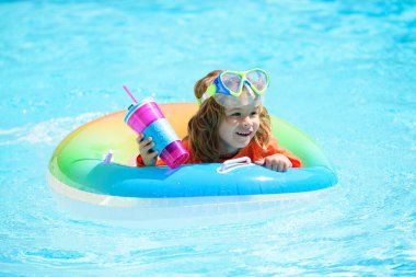 Güneşli bir günde havuzda güneş gözlüğü takan sevimli bir çocuk. Yazın havuzda kokteyl..