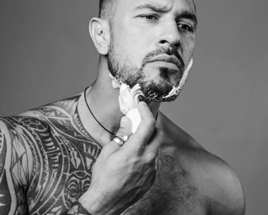 Sakallı adam berber dükkanını ziyaret ediyor. Sakallı adam berber dükkanında kuaför tarafından tıraş ediliyor. Klasik berber dükkanı traşı. Berber dükkanı klasiği.