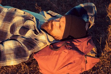 Her gün yeni bir macera. Sakallı adam yürüyüş macerası sırasında yerde dinleniyor. Hippi yürüyüşçüsü macera gezisinde sırt çantasında dinleniyor. Seyahat ve macera