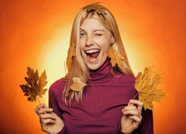 Sezonluk giysili, altın yapraklı çekici genç bir kadın. Sonbahar güneşli bir günde sonbahar kıyafetleri giyen bir kız. Moda kızları. Güzel, şehvetli bir kadının moda portresi. Yakın plan portre.