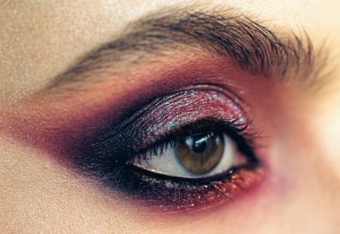 Profesyonel dumanlı gözler, özel durumlar için güzel bir kıza makyaj yapar. Göz makyajındaki parlak pigmentler. Göz makyajı konsepti. Mor dumanlı göz makyajı. Yakın çekim..