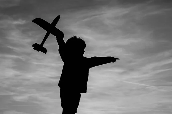 Child playing with toy plane during sunset time in evening. Child playing with model plane. Summer at countryside. — Stock Photo, Image