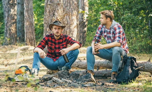 Amigos pasan fin de semana de ocio bosque naturaleza fondo. Dos personas felices sentadas alrededor de la fogata con cerveza. Los amigos disfrutan de campamento de fin de semana en bosque. Estilo de vida. —  Fotos de Stock