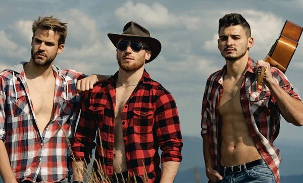 Fröhliche Freunde lachen beim Wandern mit der Gitarre. Wandergruppe auf einem Berg. Wanderer entspannen sich auf einem Berg und genießen die Aussicht auf das Tal. — Stockfoto