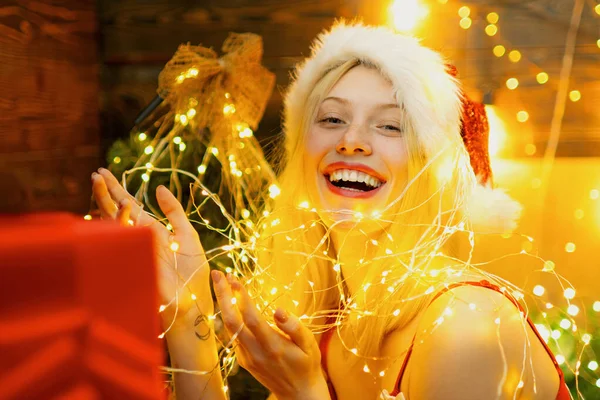 Sexy Santa mulher posando no fundo de madeira vintage. Fundo da noite com um sparkler. Preparação de Natal - menina sensual que celebra o Ano Novo. Efeito de luz piscando mágico. — Fotografia de Stock