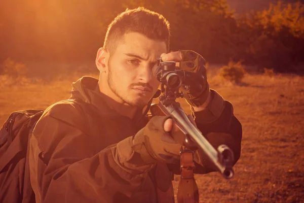 Hunter met Krachtige Rifle met Scope spotting Dieren. Rifle Hunter Silhouetted in mooie zonsondergang. Herfst jachtseizoen. — Stockfoto